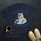 Navy blue t-shirt with bear graphic and text on a dark textured surface with a cup and shoes.
